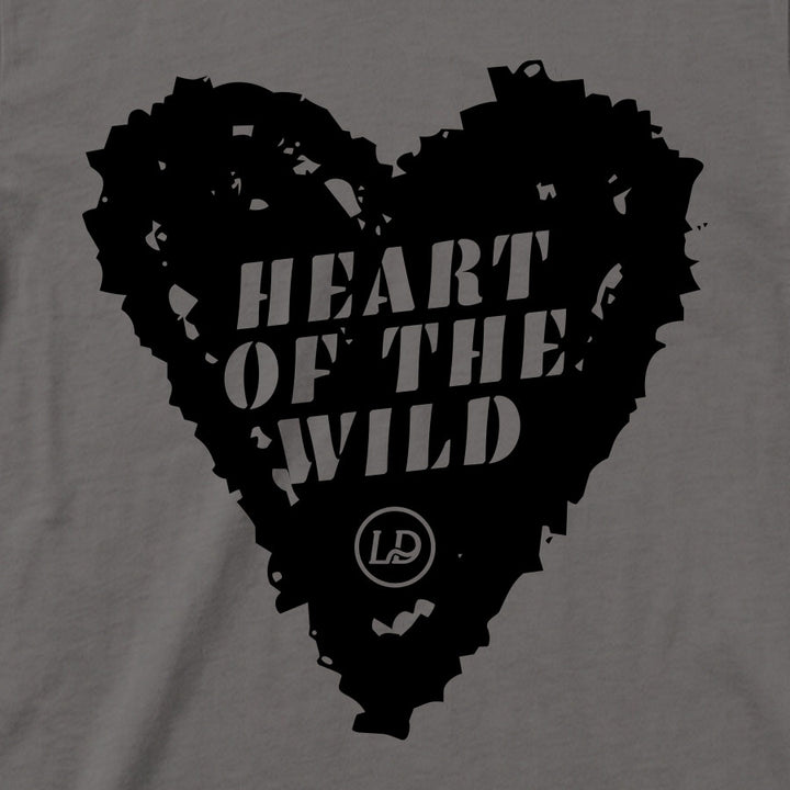 A close-up of a gray fabric surface with a large black heart-shaped graphic containing the words “HEART OF THE WILD” in white and a small circular “LD” logo near the bottom.
