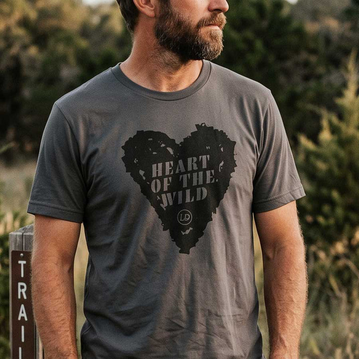 A man wearing a dark gray crewneck t-shirt with a distressed black heart graphic that reads &