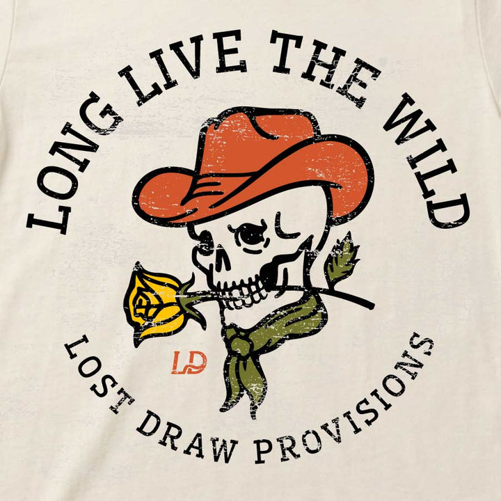 Close-up of a cream-colored t-shirt featuring a distressed graphic of a cartoon skull wearing an orange cowboy hat and holding a yellow rose. The text &