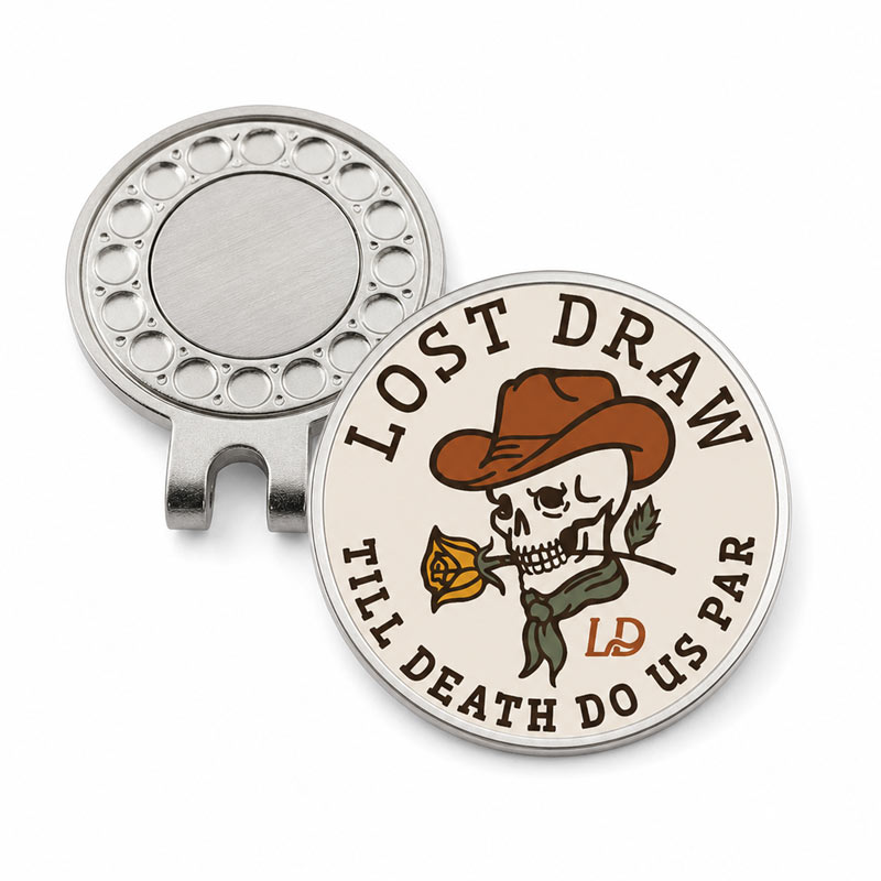 A round golf divot pin shown from both the front and back. The front features a cream-colored face with a western-themed graphic of a skull wearing a brown cowboy hat and holding a yellow rose, surrounded by the text &