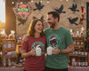 Couple Grackle Claus tee at an event drinking hot cocoa. 