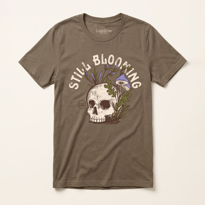 Front of the Still Blooming Jersey Tee in Vintage Brown featuring a vintage skull, lavender mushrooms, and olive green botanical artwork.