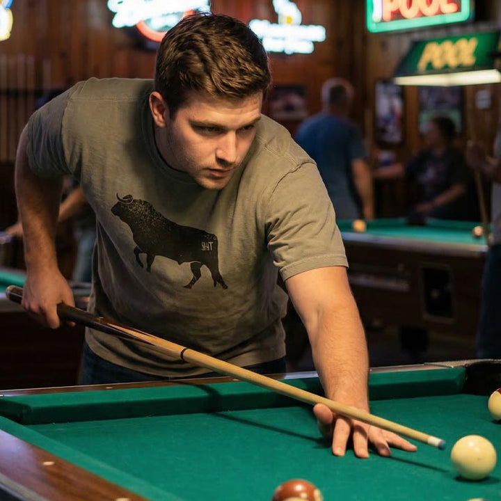 Man playing pool in a bar with neon signs in the background