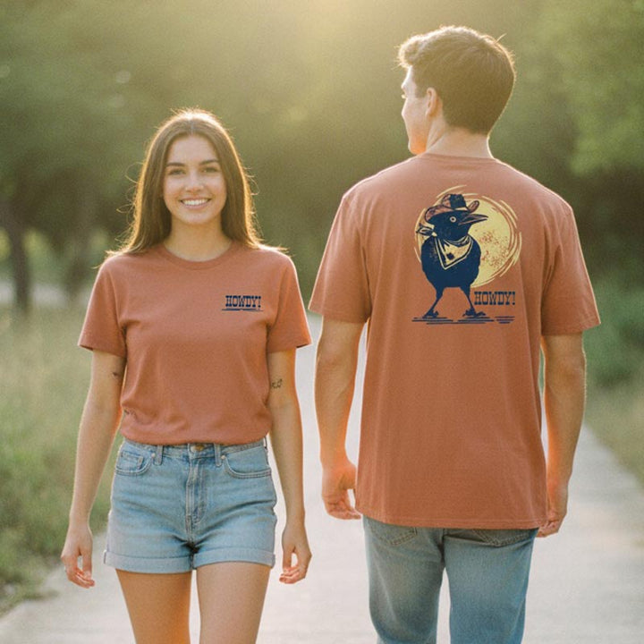 Two people wearing matching t-shirts with a design on the back, standing outdoors.