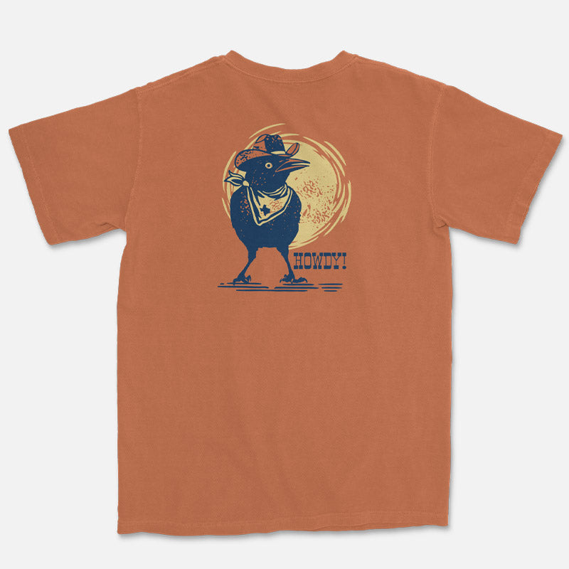 Orange t-shirt with a graphic of a grackle in a cowboy hat and 'Howdy!' text on a white background