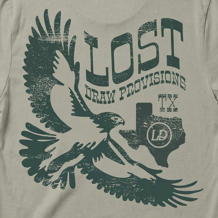 Back of the back Lost Hawk Jersey Tee featuring distressed forest-green hawk illustrations, vintage Lost Draw Provisions lettering, and Texas artwork on a Thyme green shirt.