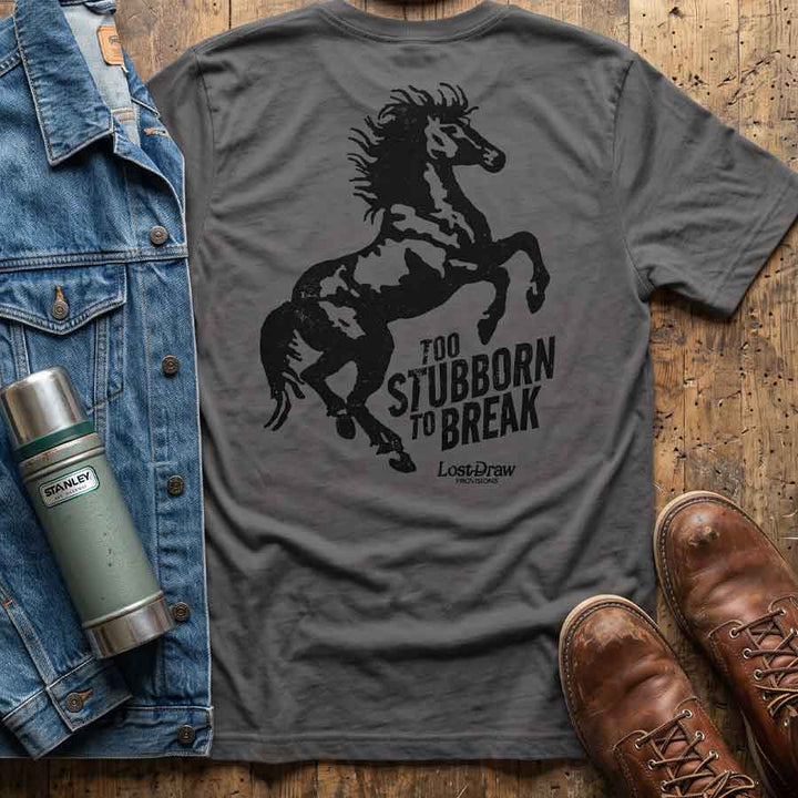 Asphalt Too Stubborn Tee displayed with a denim jacket, leather boots, and a thermos, featuring the large rearing horse back graphic.