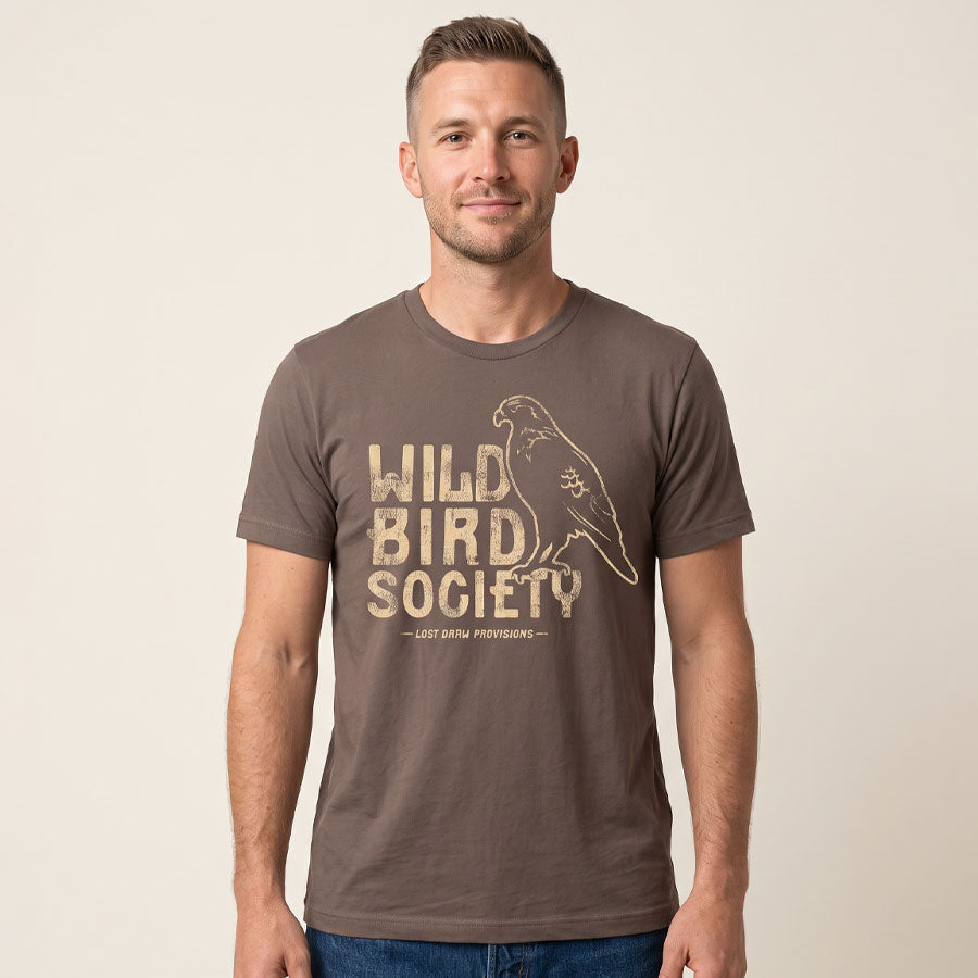 Man wearing the Cocoa Wild Bird Society Tee, showing the large cream bird graphic on the front.