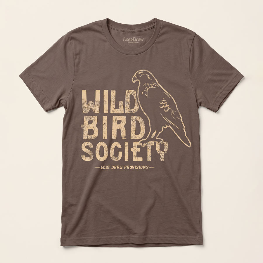 Front of the Wild Bird Society Jersey Tee in Cocoa featuring a distressed cream bird illustration and vintage lettering.